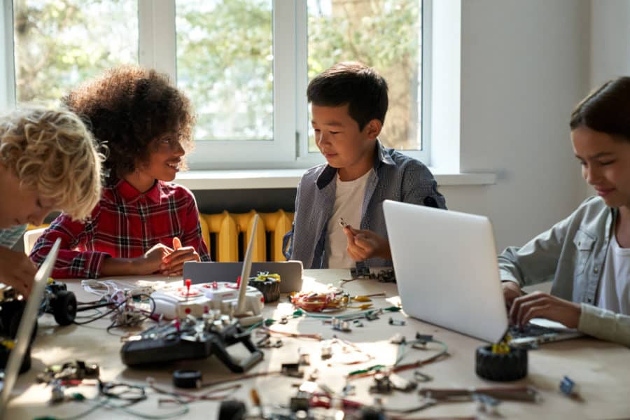 case study: Class of multiracial diverse schoolkids using gadgets to build robots.