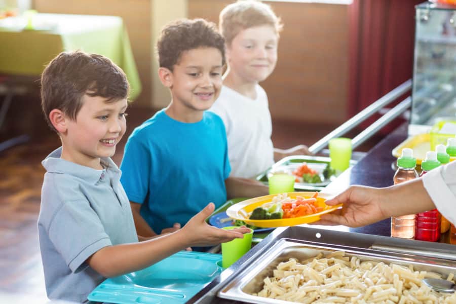 school children being served lunch after using a lunch cashier system